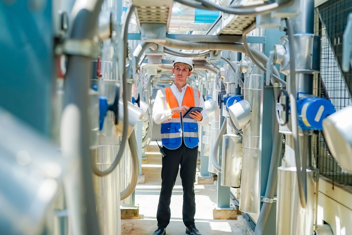 Man in safety vest and hat standing in industrial setting