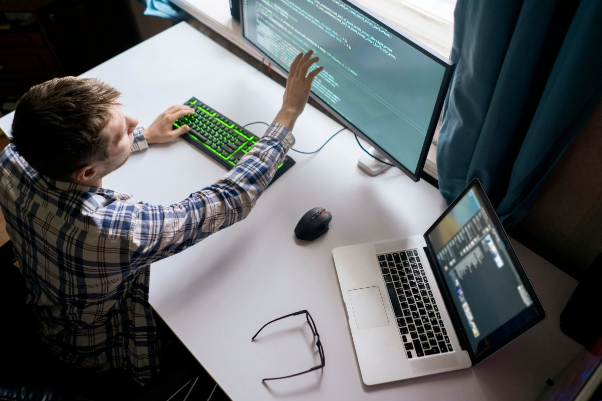 Overhead shot of a man at his desk, touching his monitor with his finger for some reason